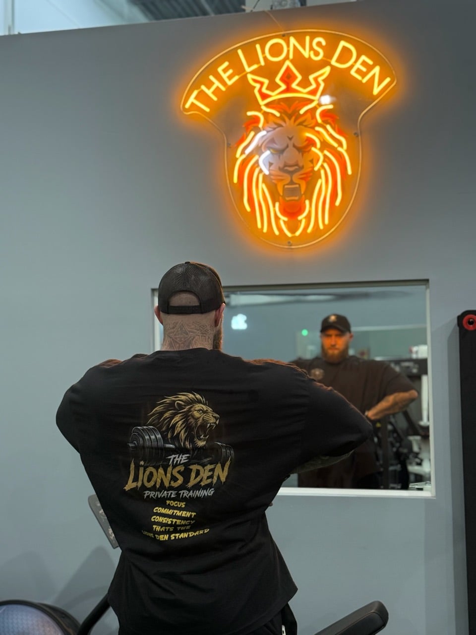 Kyle Mamane beneath The Lions Den neon sign inside the private training room